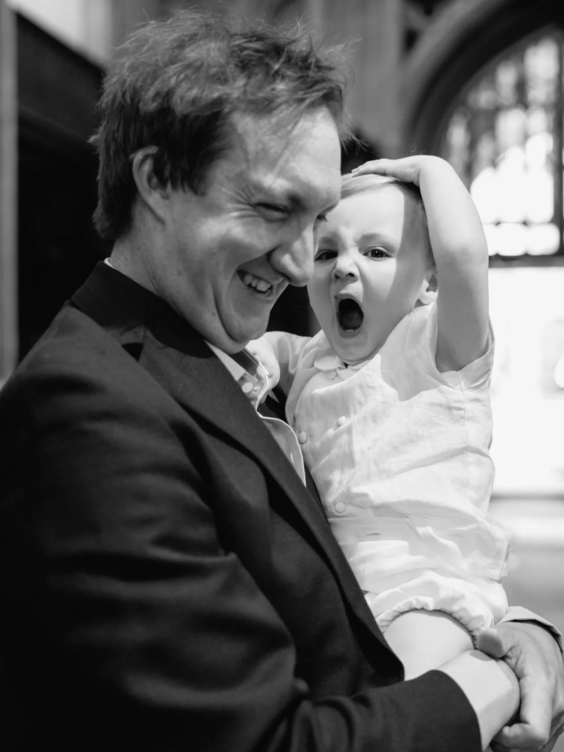 Baby boy yawning in father's arms