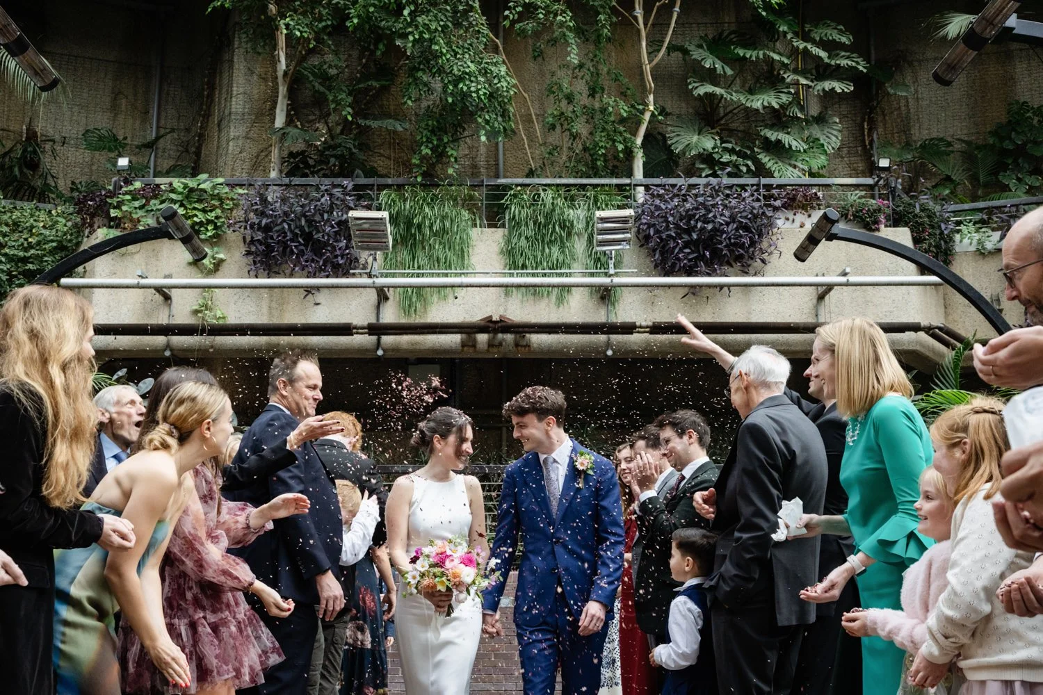 Coming down the aisle to confetti in the Barbican Conservatory.