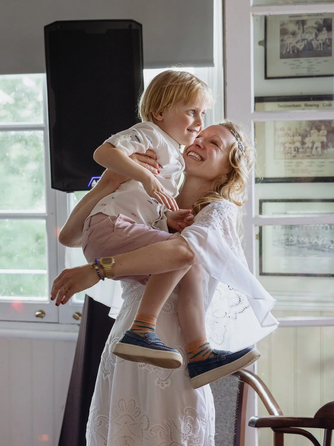 Bride lifting her four year old son up and smiling at  him.