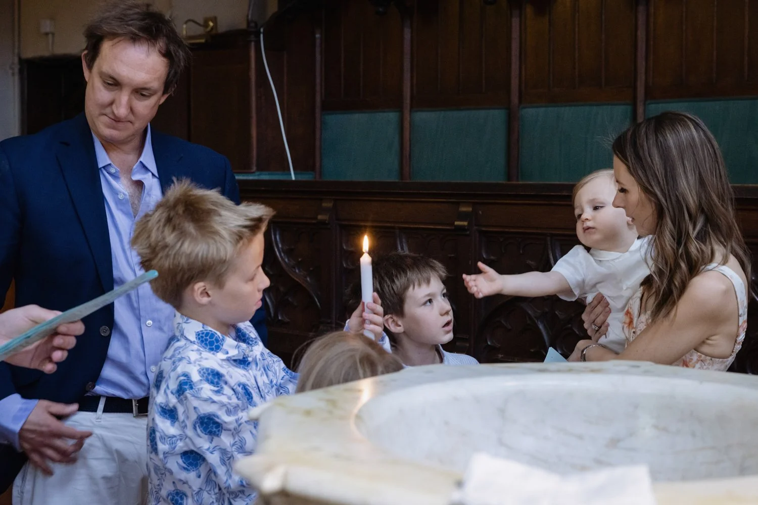 Baby being christened reaches out to lit candle