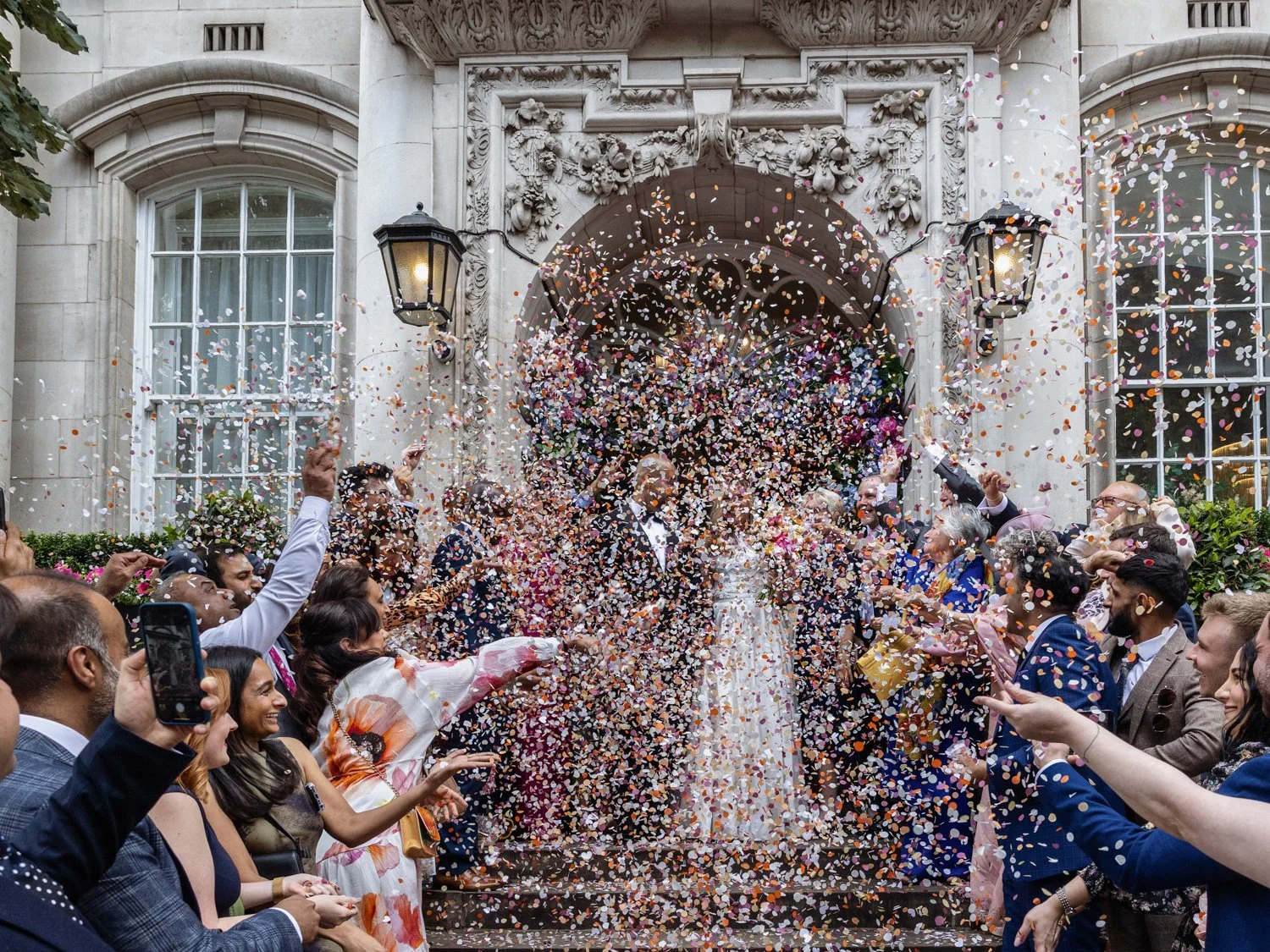 A mass of confetti hides the bride and groom as they exit onto the steps of Old Chelsea Town Hall.