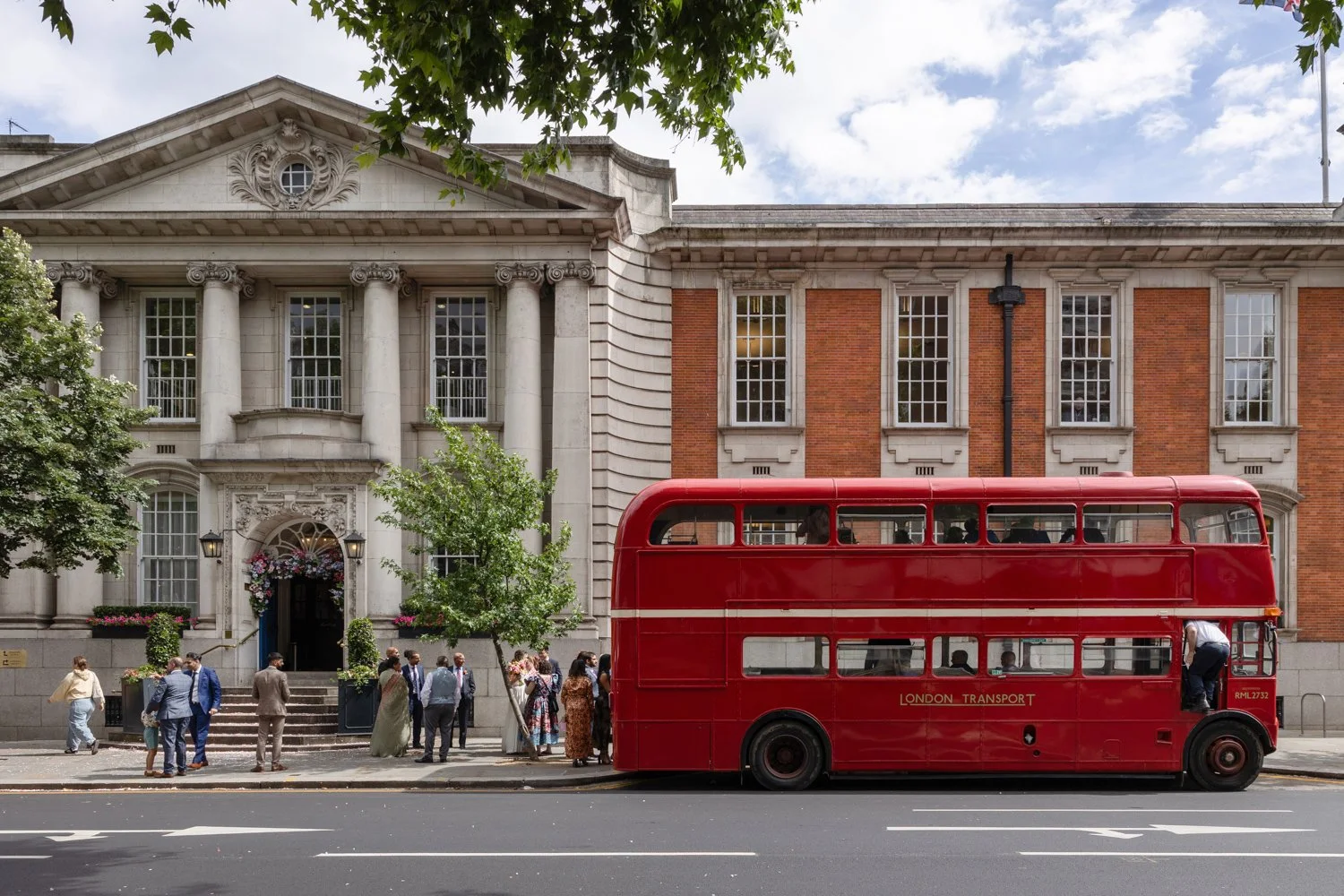 view of Old Chelsea Town Hall and bus driver climbing into red routemaster bus.