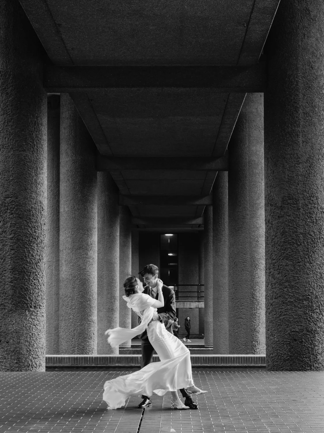 Romantic image of bride and groom on the lakeside terrace at the Barbican Centre.