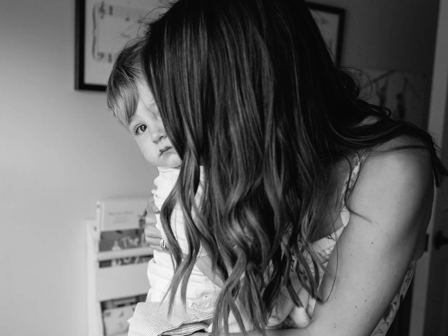 Baby boy peering out from behind his mother's curtain of hair.