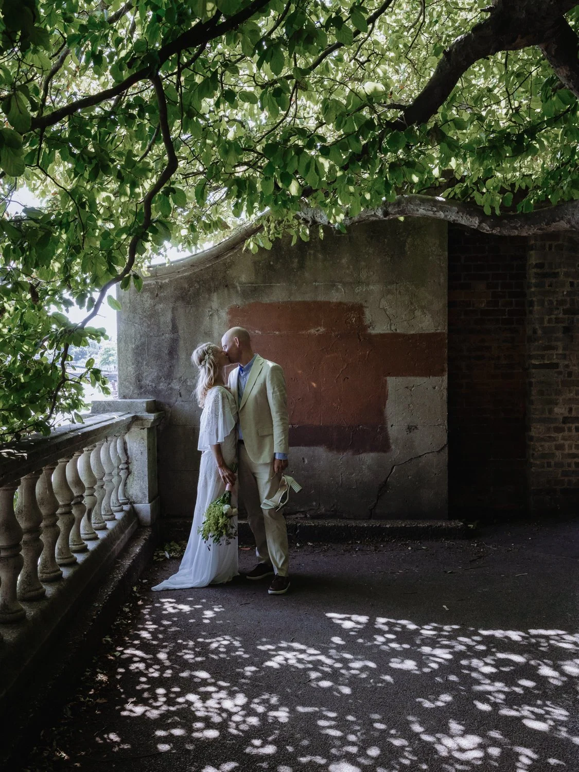 Bride and  Groom at the riverside in Twickenham in dappled light.