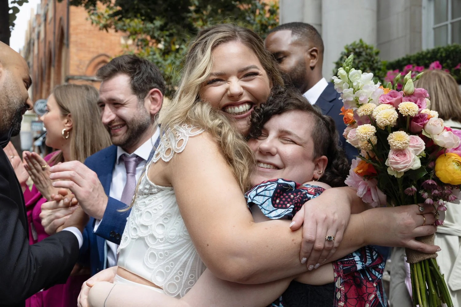Bride and best friend in a very strong hug close up with both smiling.