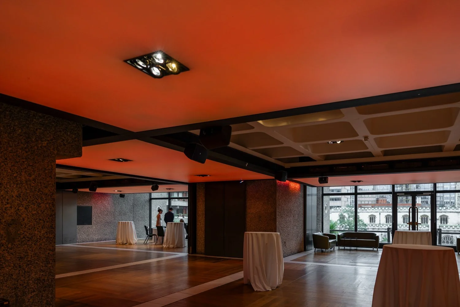 Orange neon lighting creating a warm orange mood on level 3 of the Barbican where the bride and groom can be seen in the distance having their interview with the registrars.