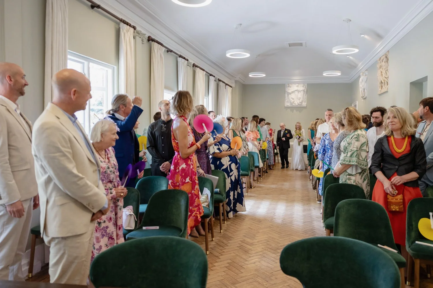 Entrance of bride and father at York House with the groom smiling and his mother looking at him.