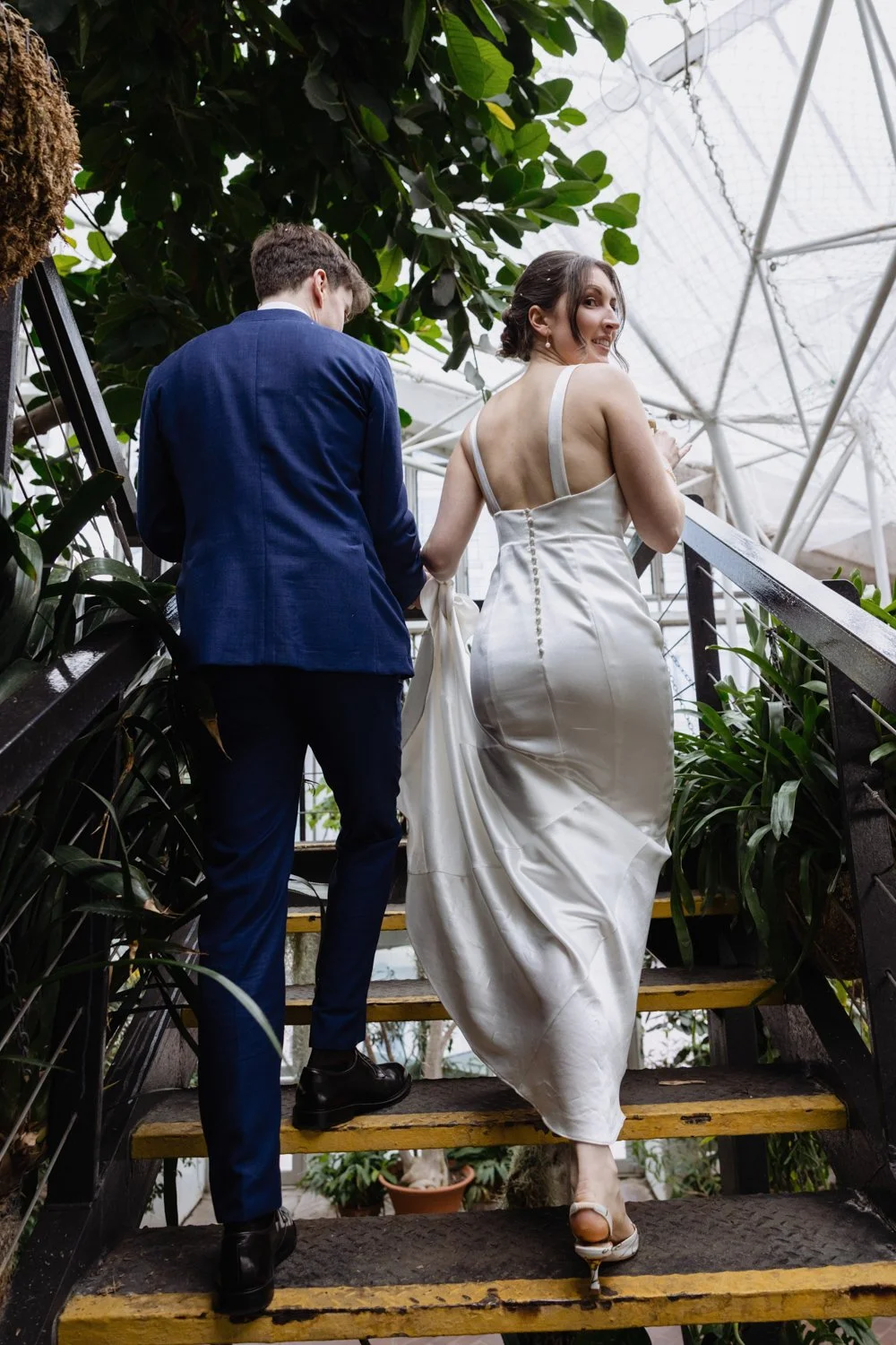 Bride and Groom climb staircase  with the bride turning around to look back