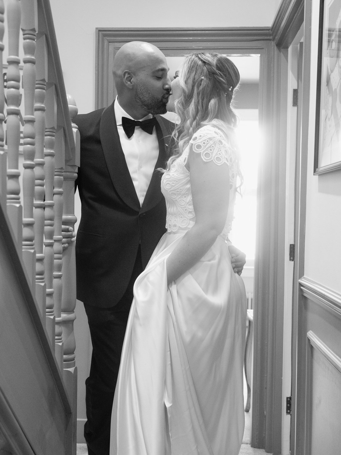 Bride and Groom kiss on the staircase of their home.