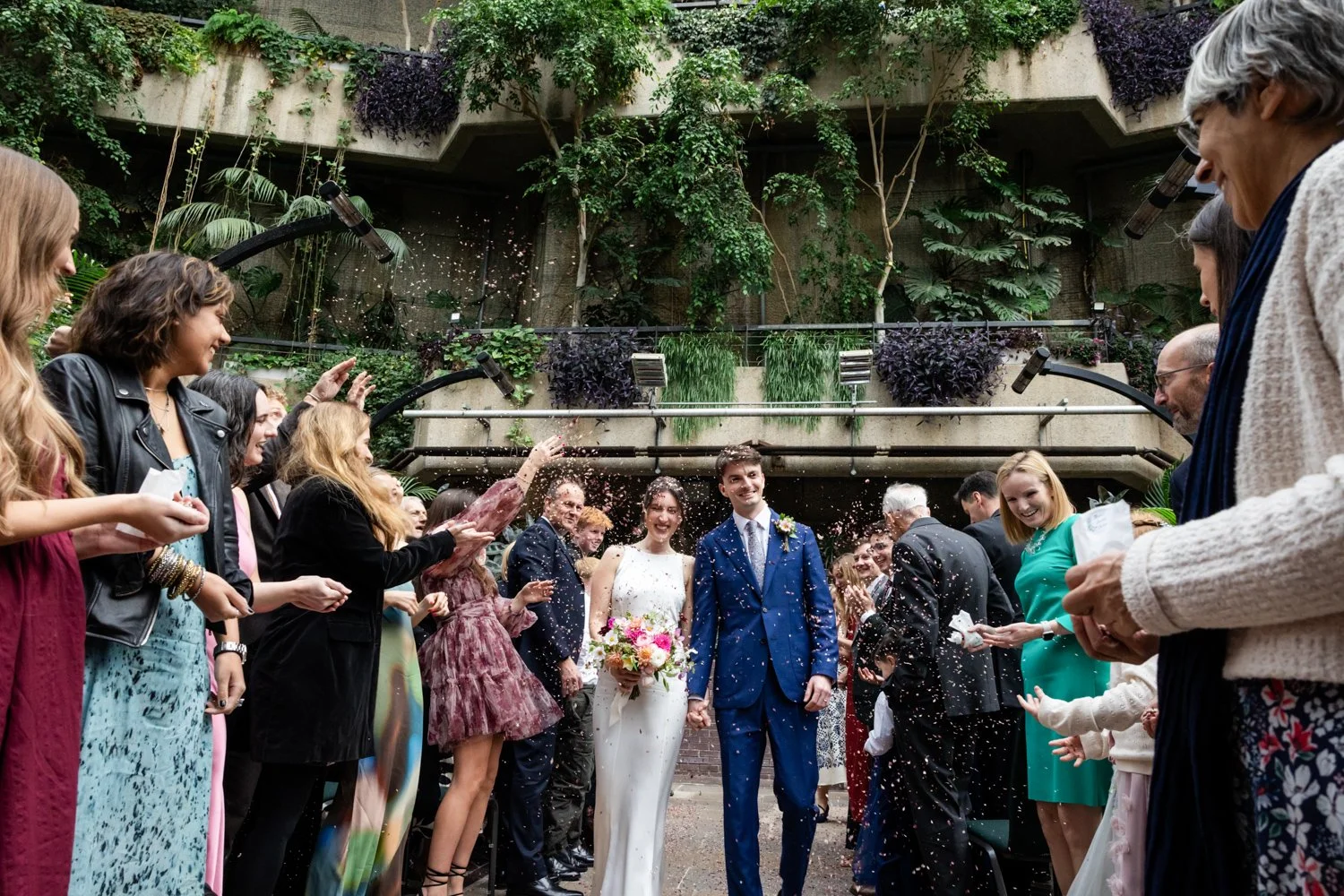 Bride and Groom exit the Conservatory at the Barbican to a garage of colourful confetti