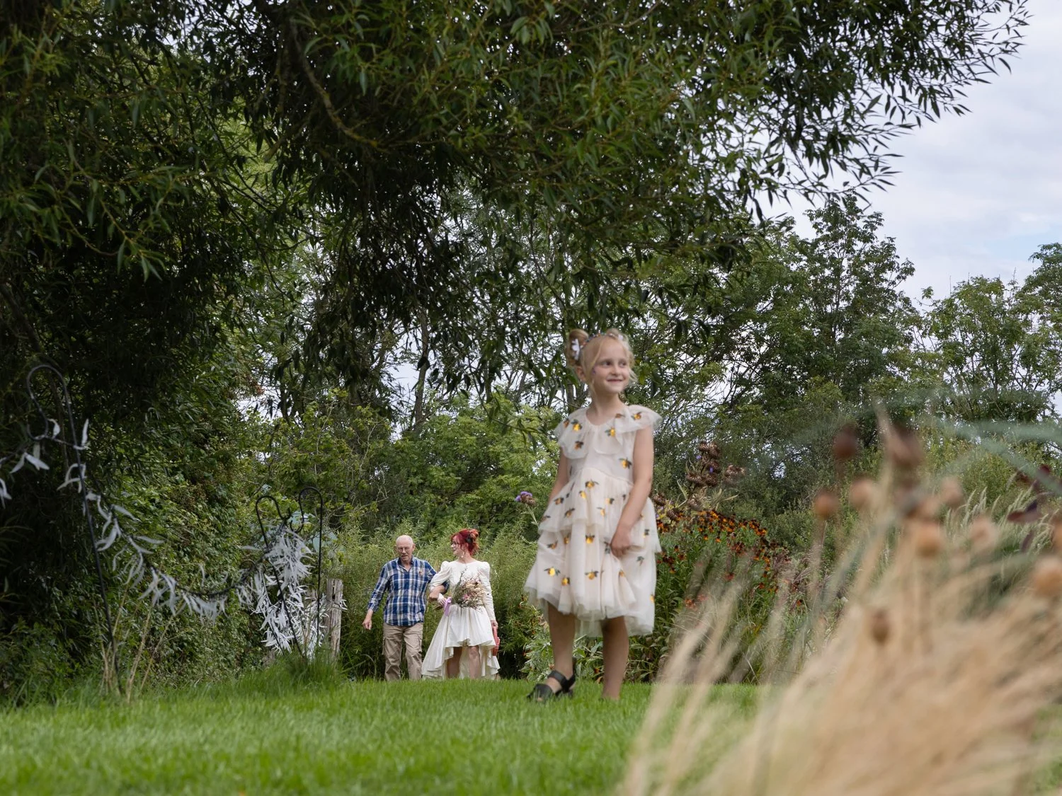 Bridesmaid leading bride and father towards he ceremony.