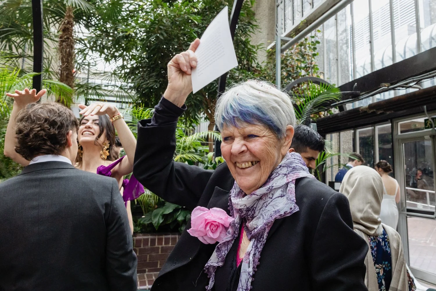 A woman guest waves and smiles at the bride and groom as they exit