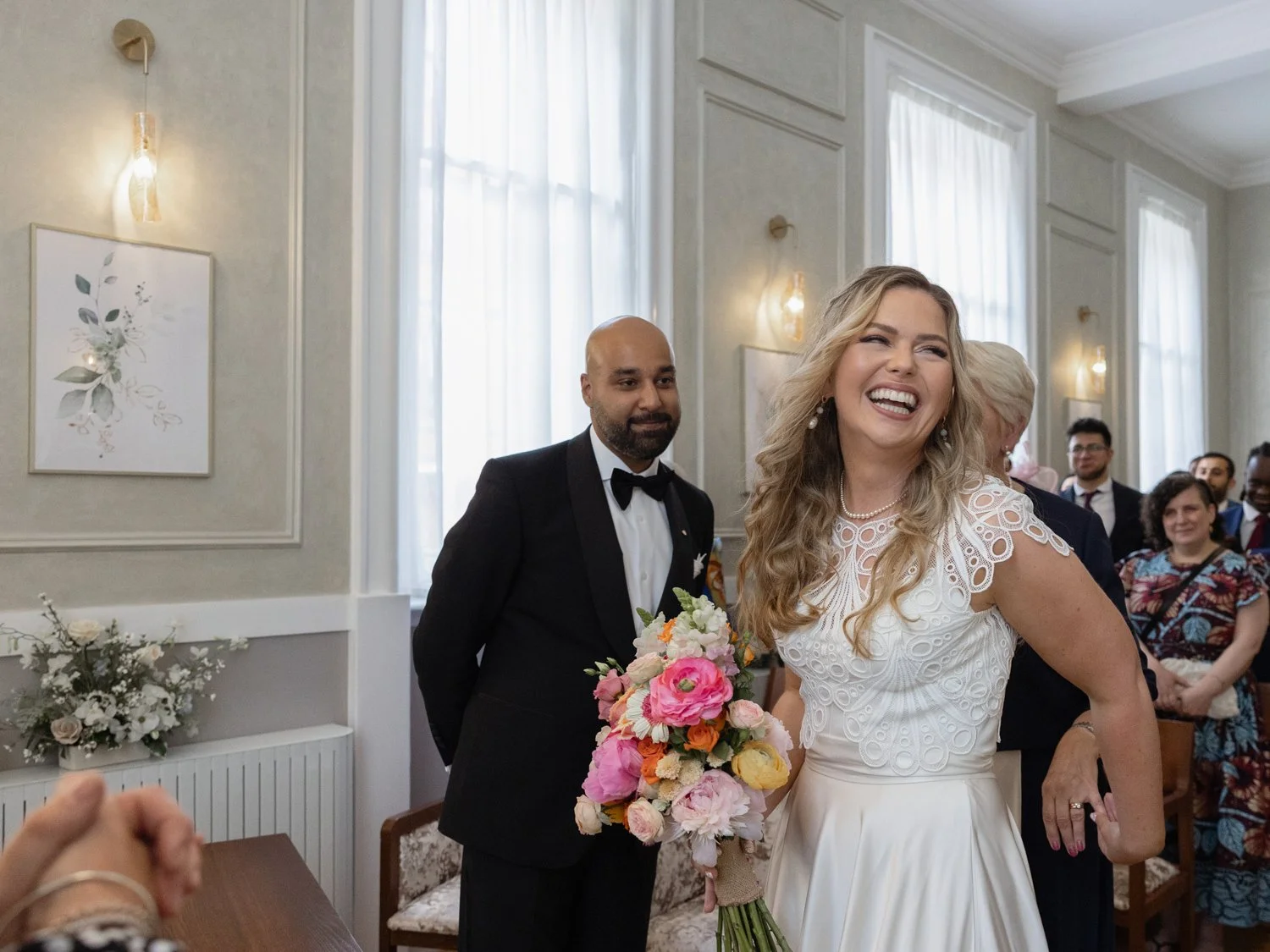 Bride laughing in Brydon Room at Old Chelsea Town Hall with groom in the background smiling
