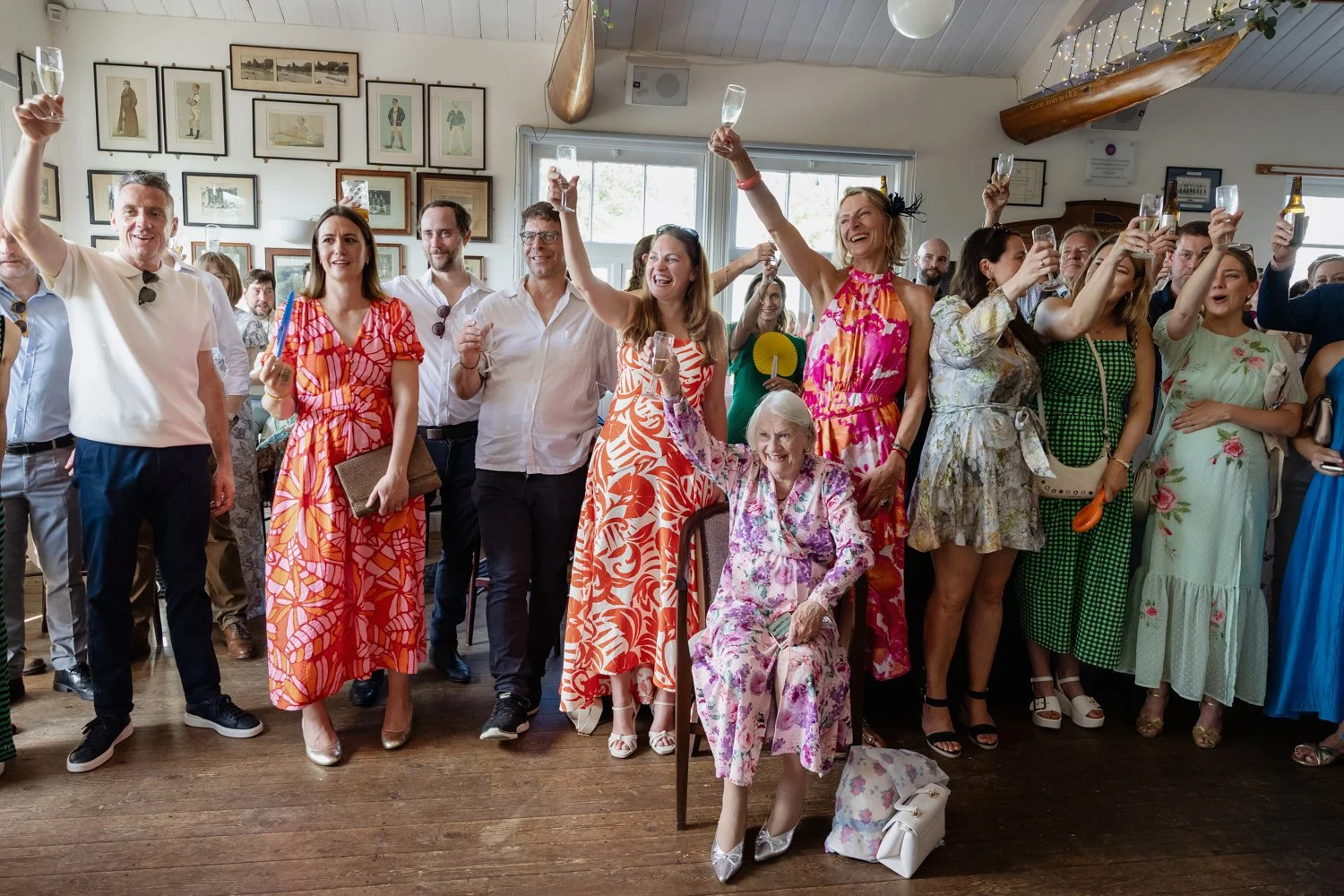 Guests in colourful bright outfits raise their glasses to the bride and groom.