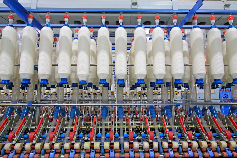 Rows of yarn bobbins on spinning machines in a textile mill.
