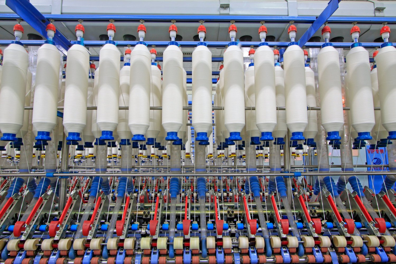 Rows of yarn bobbins on spinning machines in a textile mill.