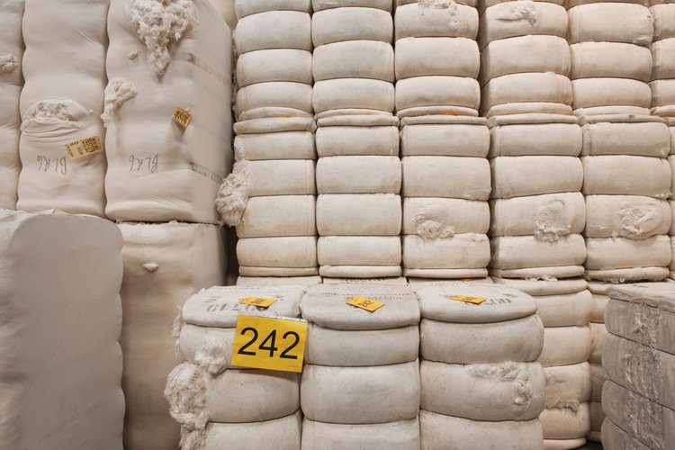 Stacks of white fibre bales in a warehouse, with yellow numbered labels attached.