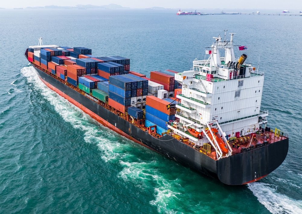 A large cargo ship loaded with colourful shipping containers sailing on the ocean.