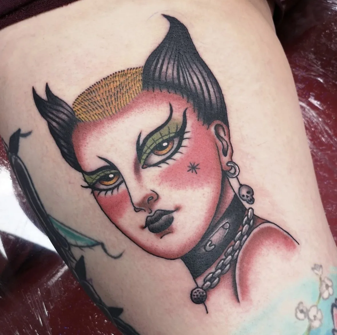 Tattoo of of a punk woman with piercings and make up.
