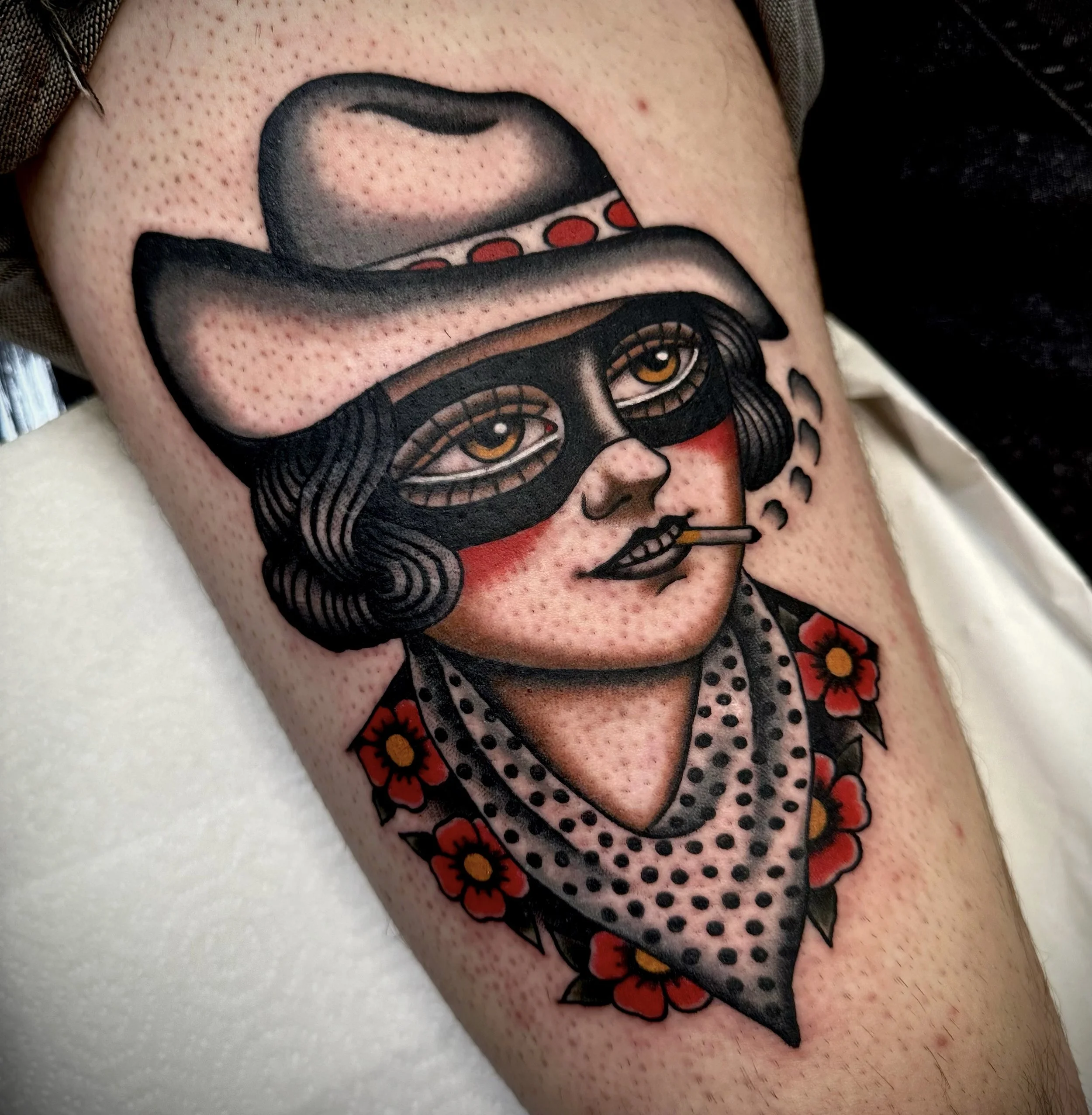 Tattoo of a cowgirl with black eye mask, smoking with a bandana around her neck.