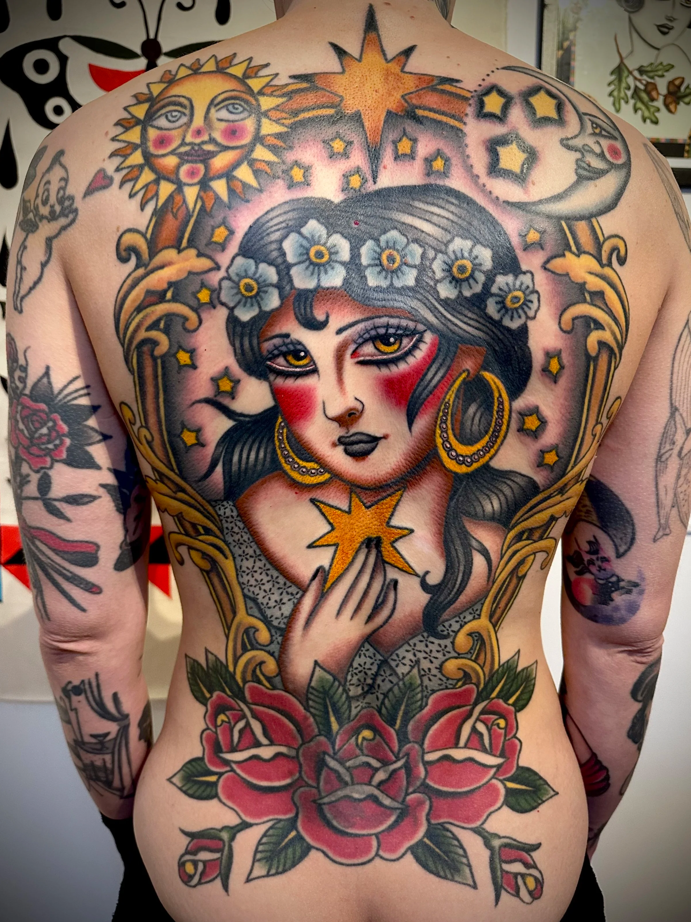 back piece tattoo of celestial woman with stars and moon, flowers and a frame around her.