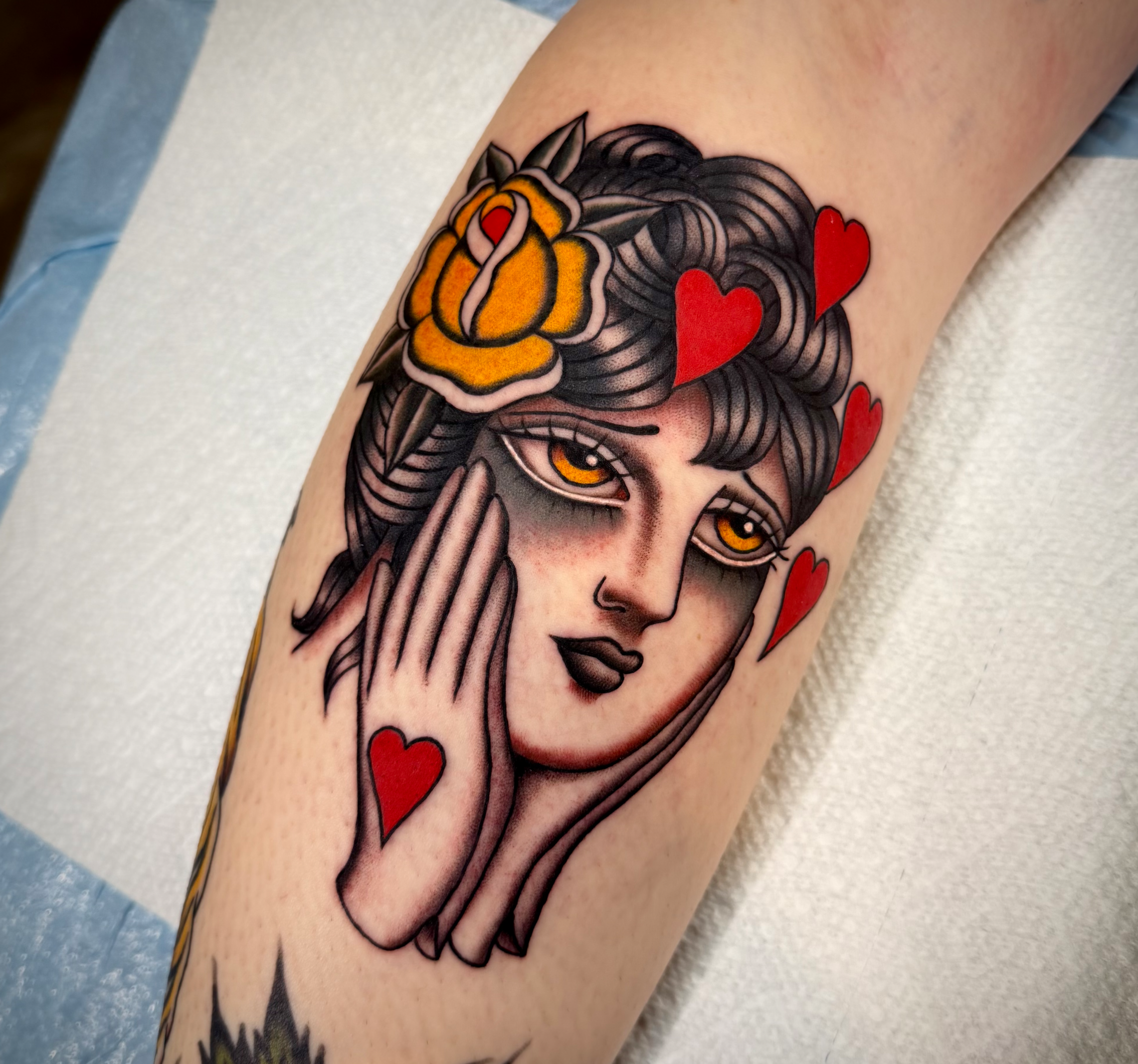 Tattoo of a woman in love, hearts around her head with yellow rose in hair and wearing gloves.