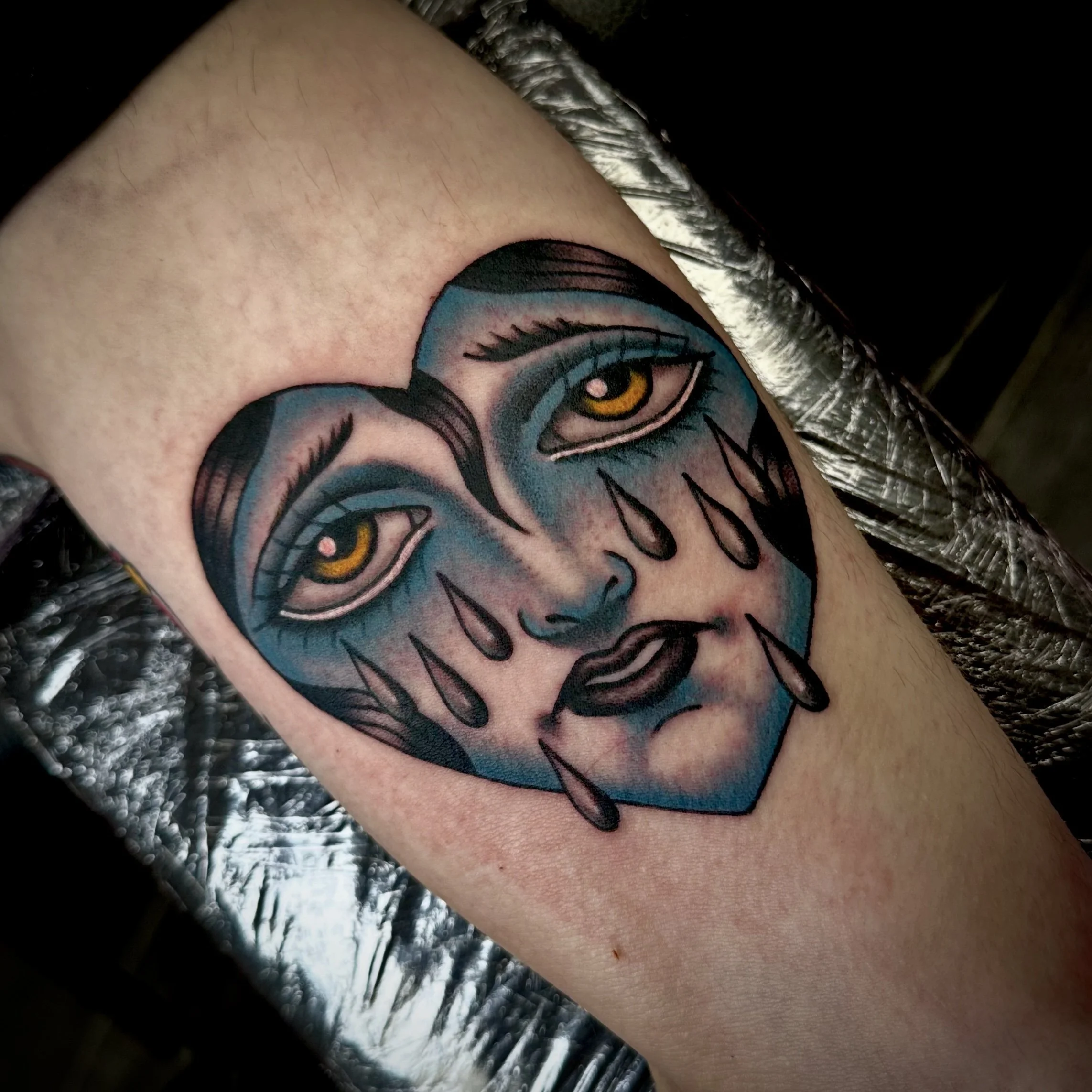 Heart tattoo with crying face inside.