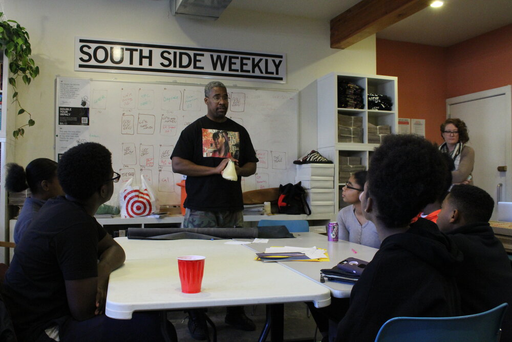  Person holding a shoe form and discussing it with students sitting around a table. Credit: Mae Morris 