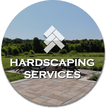 Logo for Hardscaping Services with a geometric icon above the text on a background of a paved outdoor area with trees.