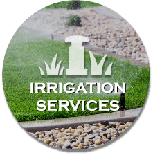 A landscaping sign that says Irrigation Services in a yard with grass, stones, and mulch.