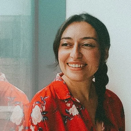 Dina Hassan, nutritionist, a smiling woman with dark hair in a braid, wearing a red floral shirt, looking to her left.