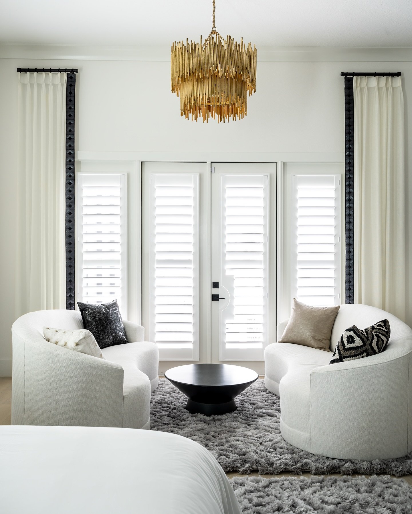 Step into a bedroom that embodies the essence of modern luxury! With its inviting plush textures and a refreshing soft white palette, this space is elevated by striking black and gold accents that add a touch of drama. The sculptural lighting casts a