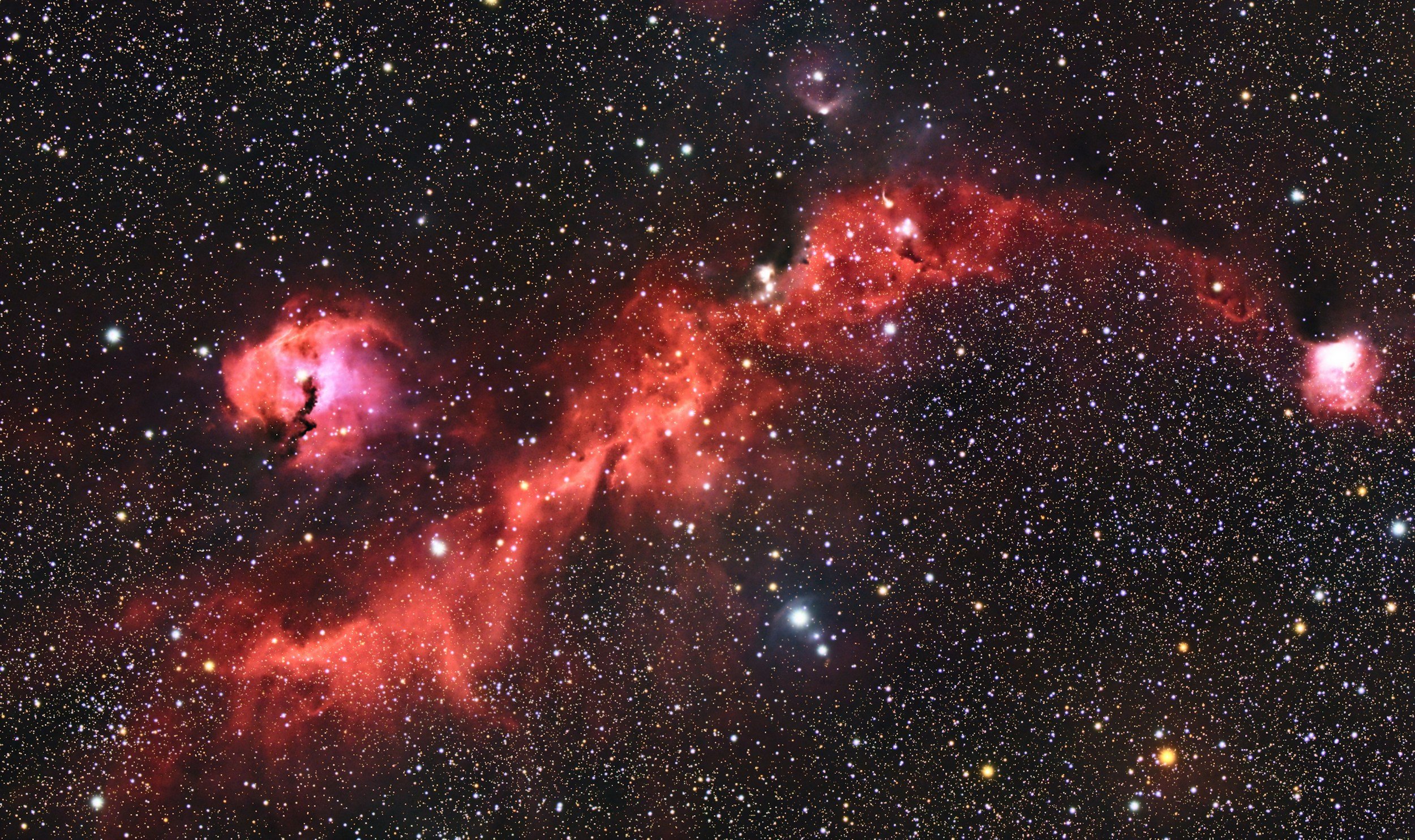 Milky Way galaxy stretching across the night sky with deep reds and celestial hues, stars sparkling in a vast cosmic landscape