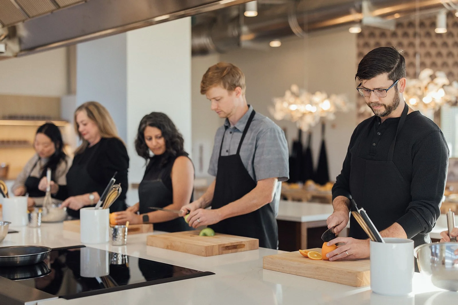 Guests in aprons cooking together during a hands-on public cooking class at Food Lab Denver
