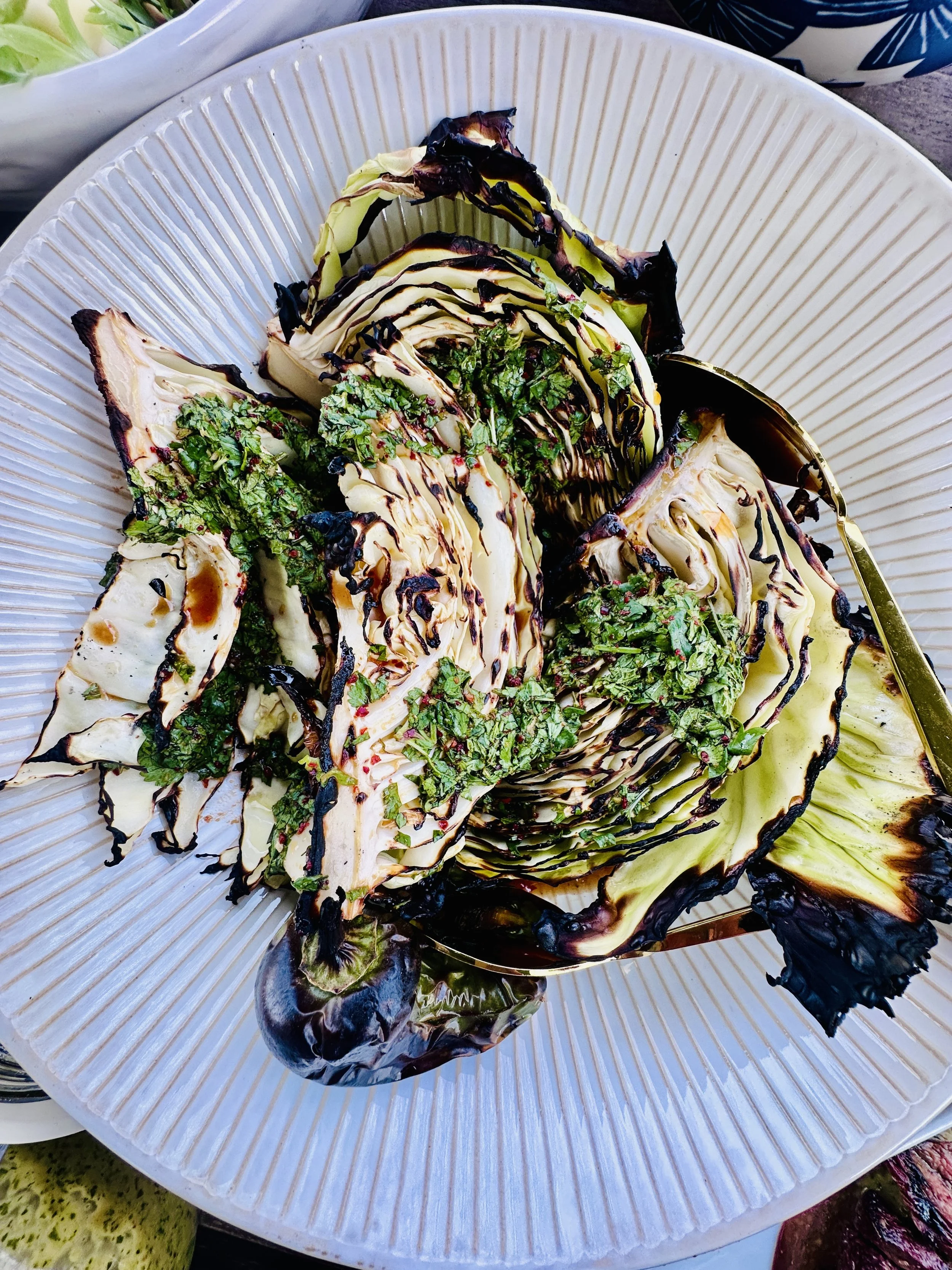 Grilled cabbage with Thai-inspired lime sauce, fresh herbs and charred edges on a white plate