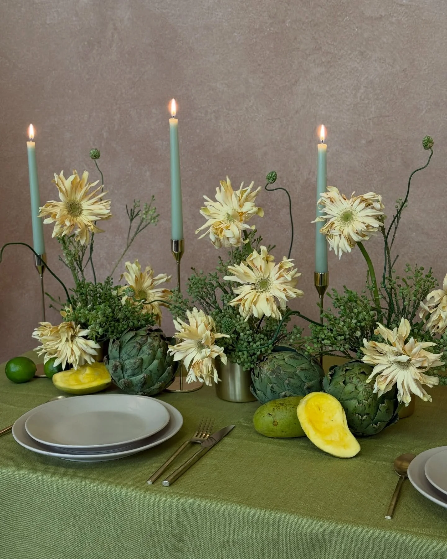 MARCH MOOD | a floral tablescape designed with gerbera daisies, berries, and snake allium paired with artichoke, mangoes and limes to style the table.

March&rsquo;s Mood Board is an ode to the color green with a gentle pairing of cream for an overal