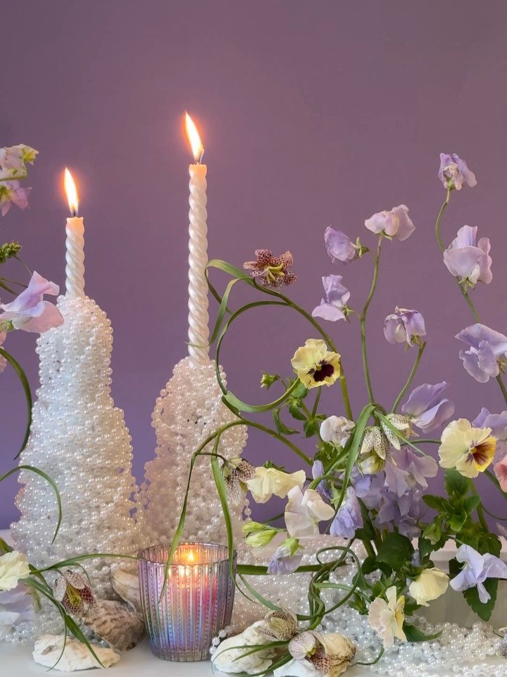 MAY MOOD | Pearls, candlelight, and spring flowers are the themes behind May&rsquo;s floral design interpretation. Pearlescent features shimmer throughout this carefully curated floral tablescape. Sweet peas, fritillaria, pansies, and foxglove dance 