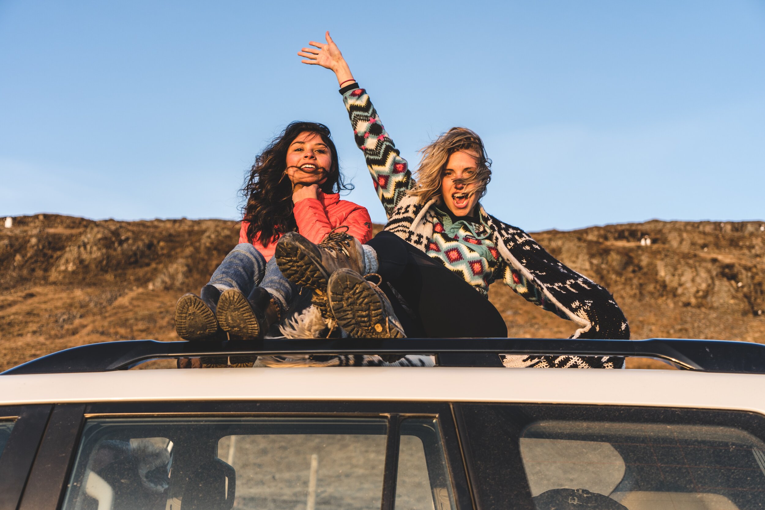 two girl sitting on the roof of a car in Namibia