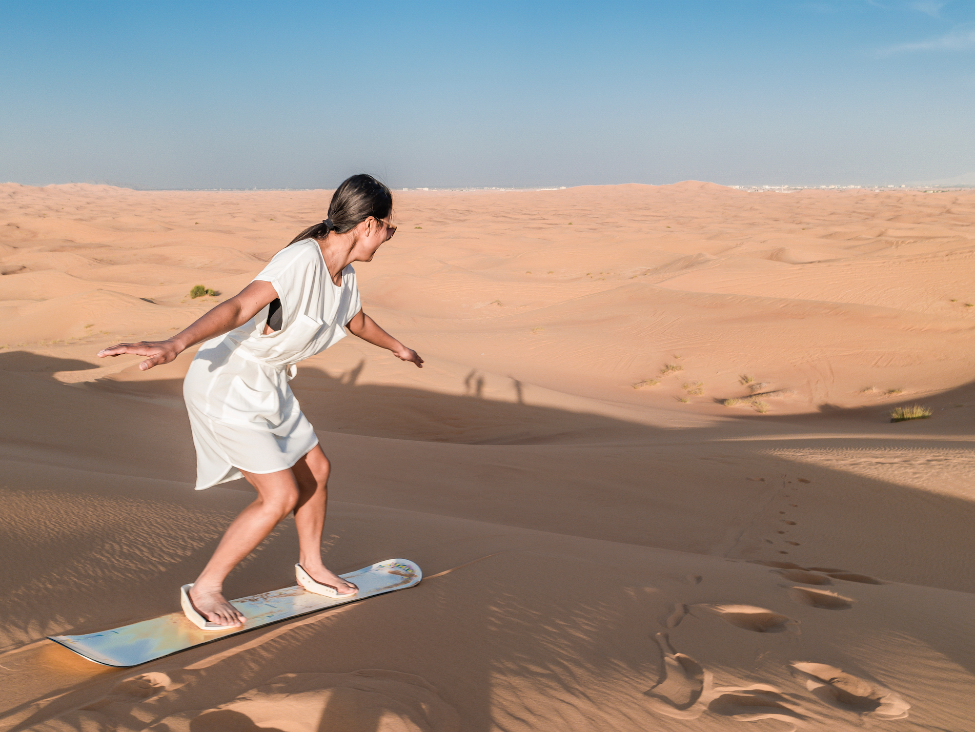 a woman sandboarding on a sand dune