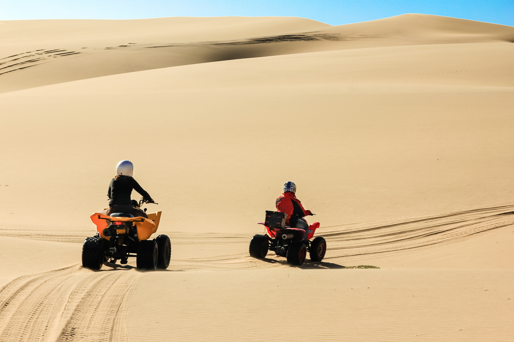 two people on quad bikes through the dunes in the desert of namibia