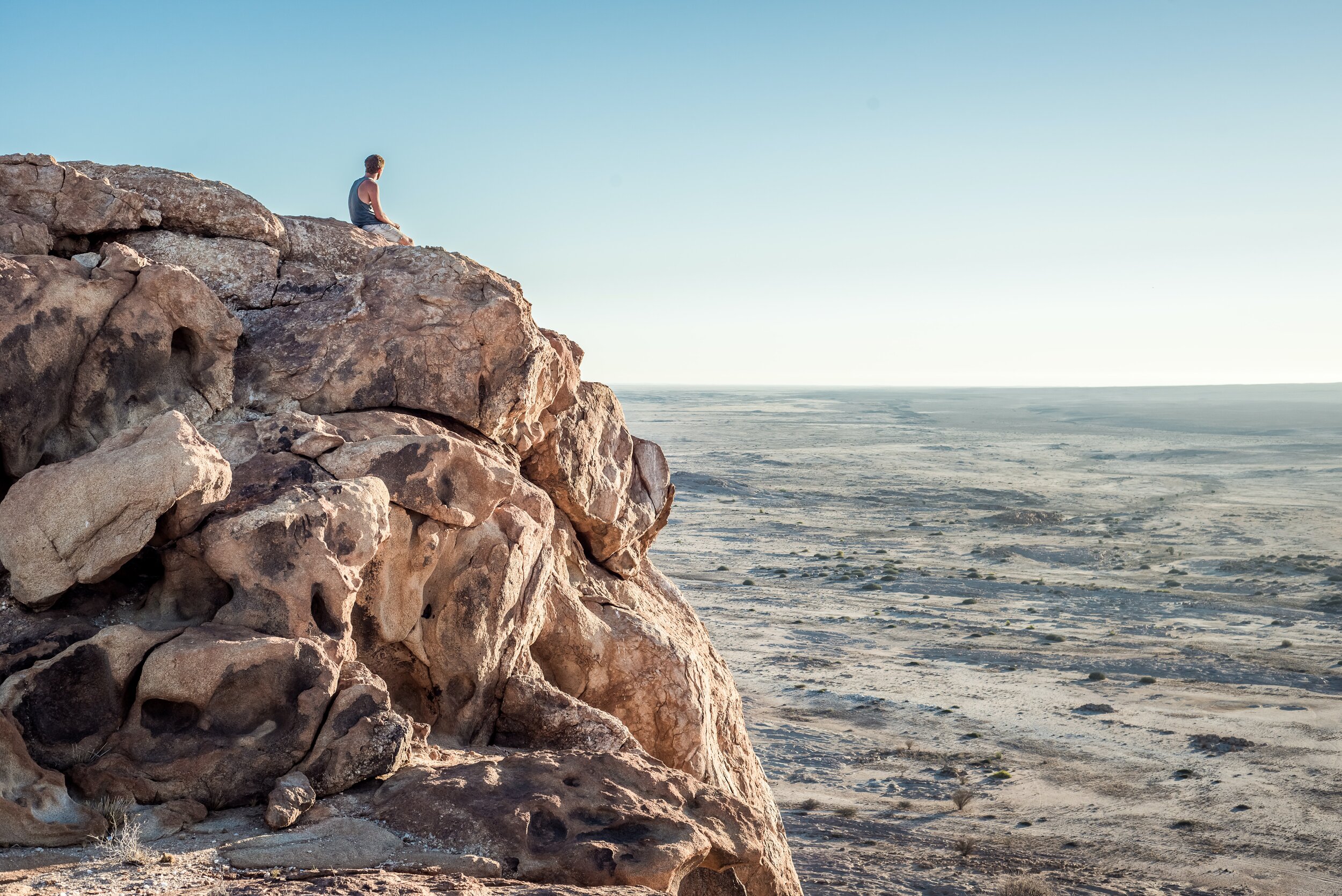 man sitting on the rock overlooking the desert