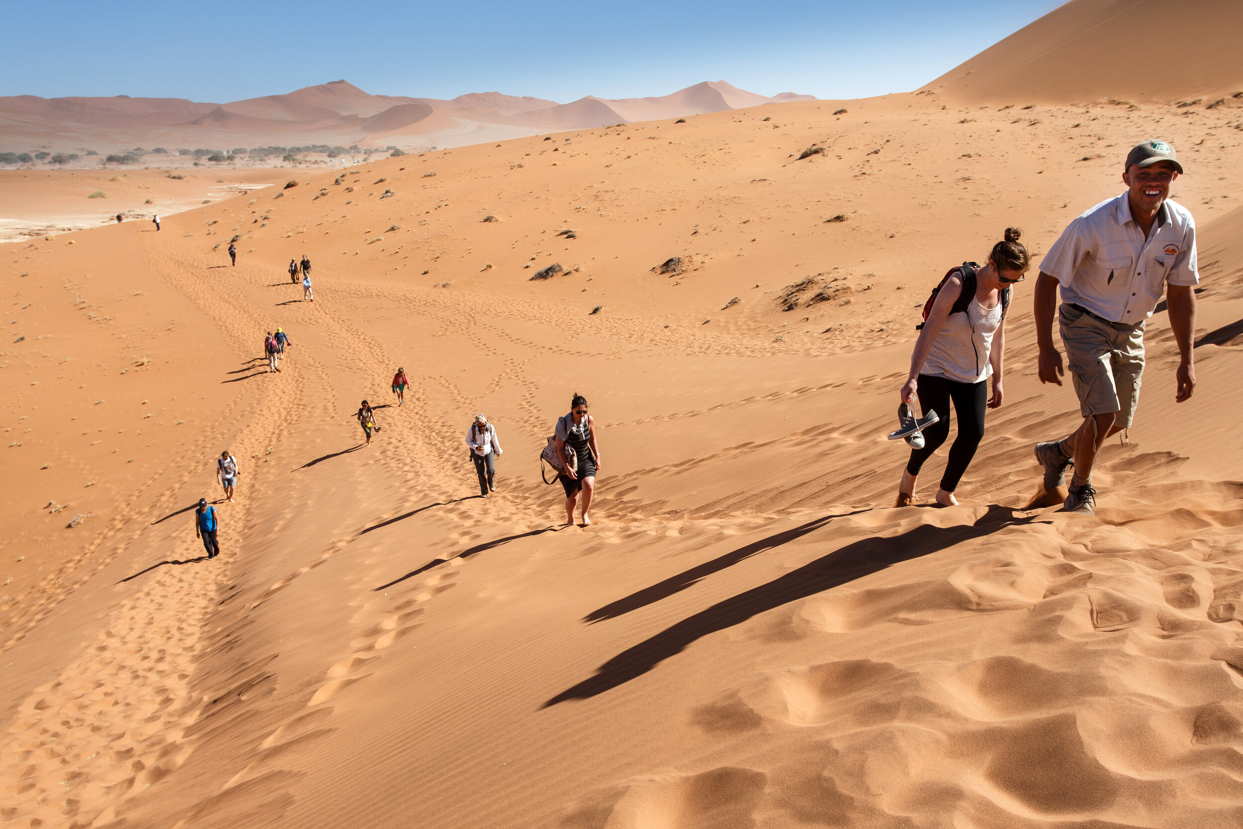 people walking up dunes