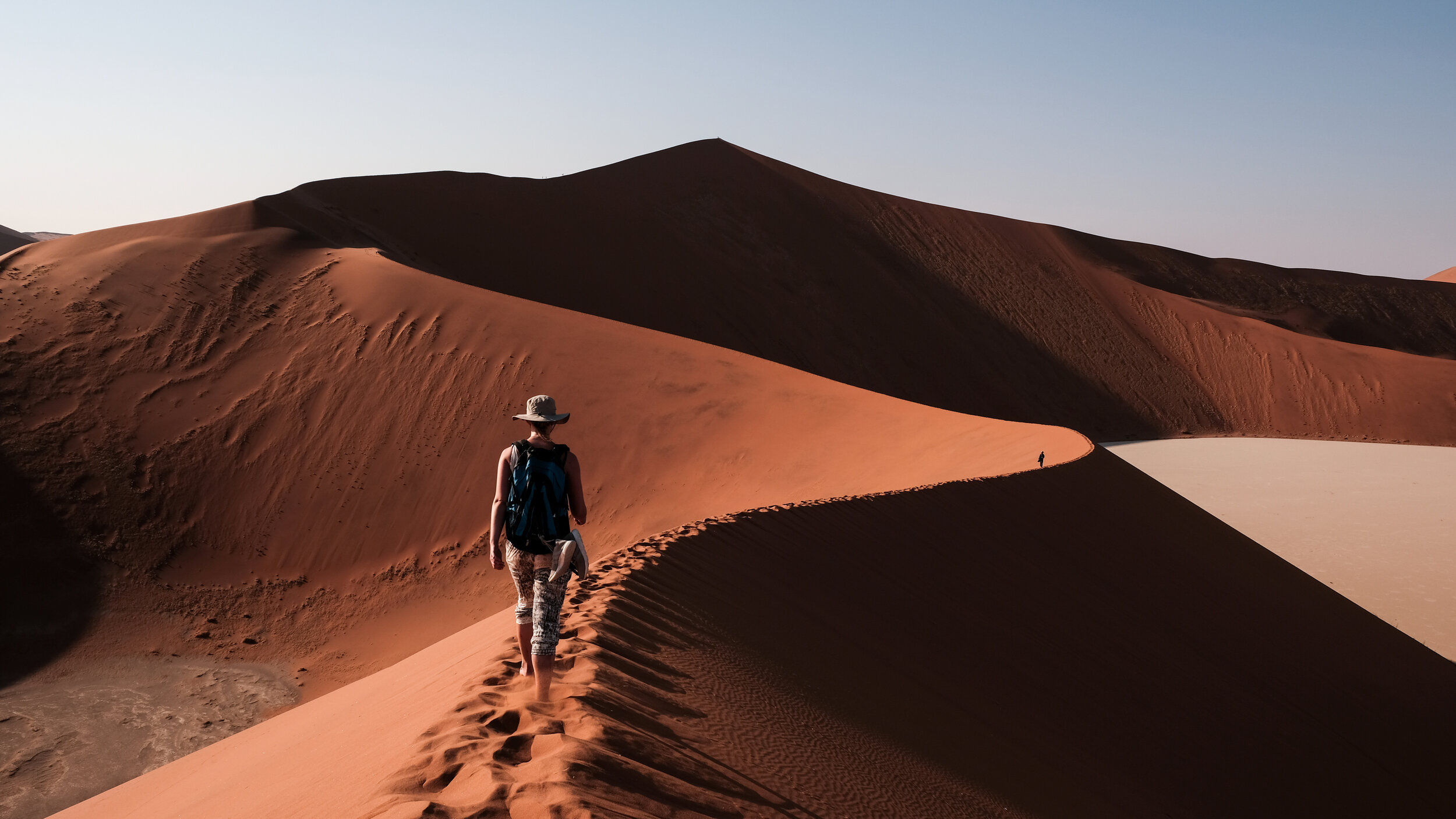 A traveller hikes across a sand dune