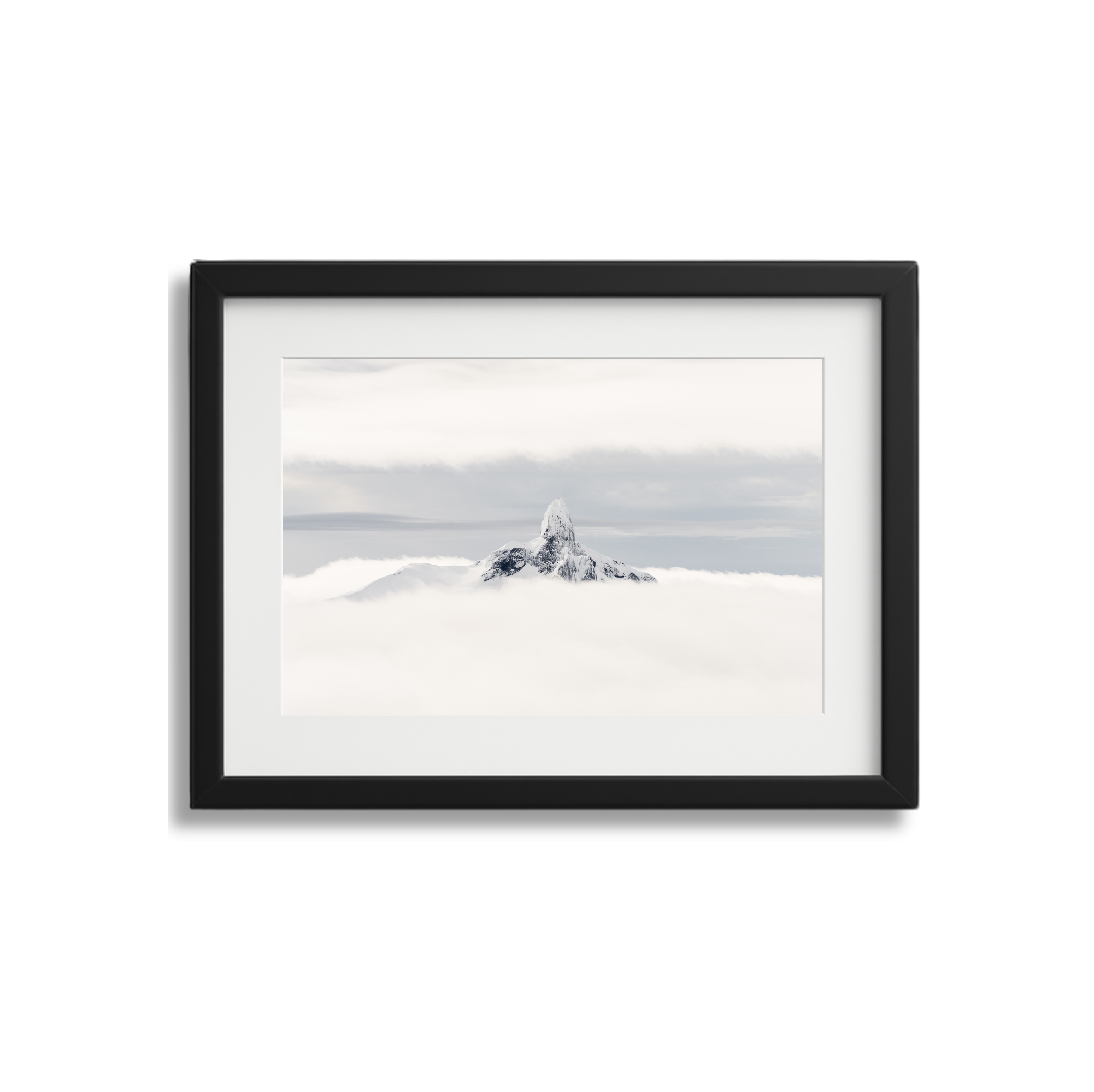 Framed photograph of a snow-capped mountain peak emerging above clouds, with a partly cloudy sky.