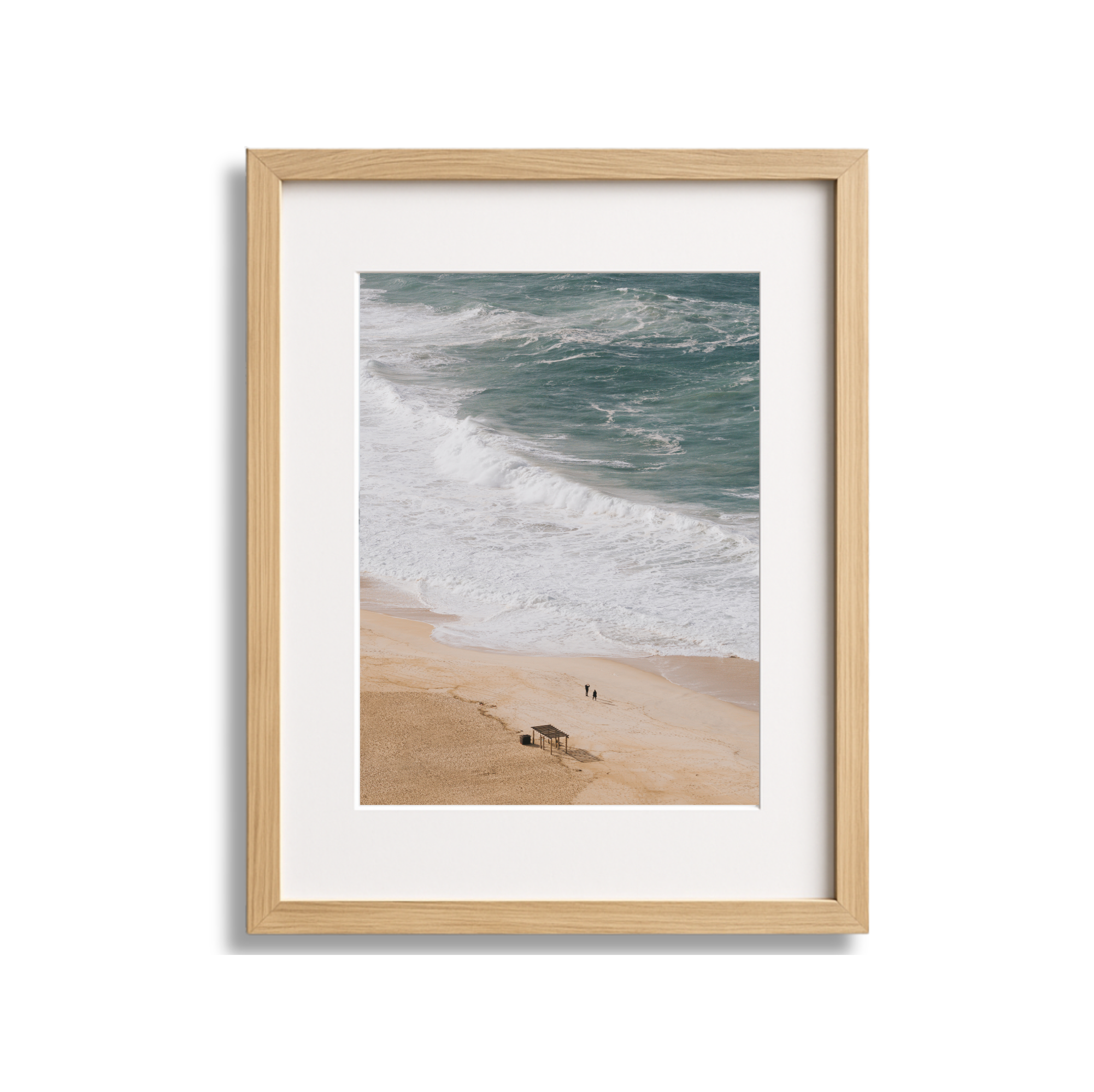 Framed photograph of a beach with sand, waves, and two people walking along the shore.