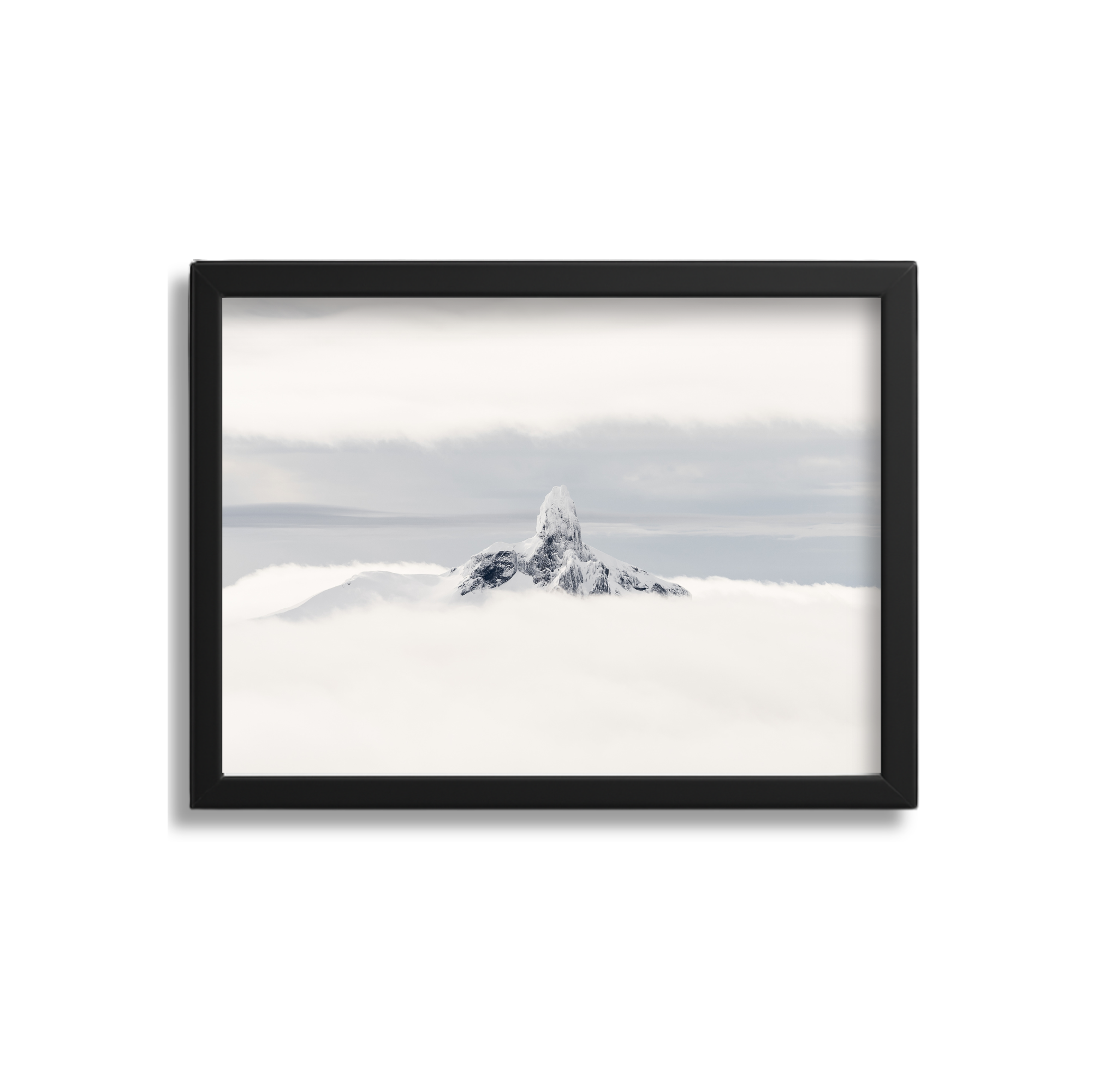Framed photograph of a snow-capped mountain peak surrounded by clouds and a cloudy sky.