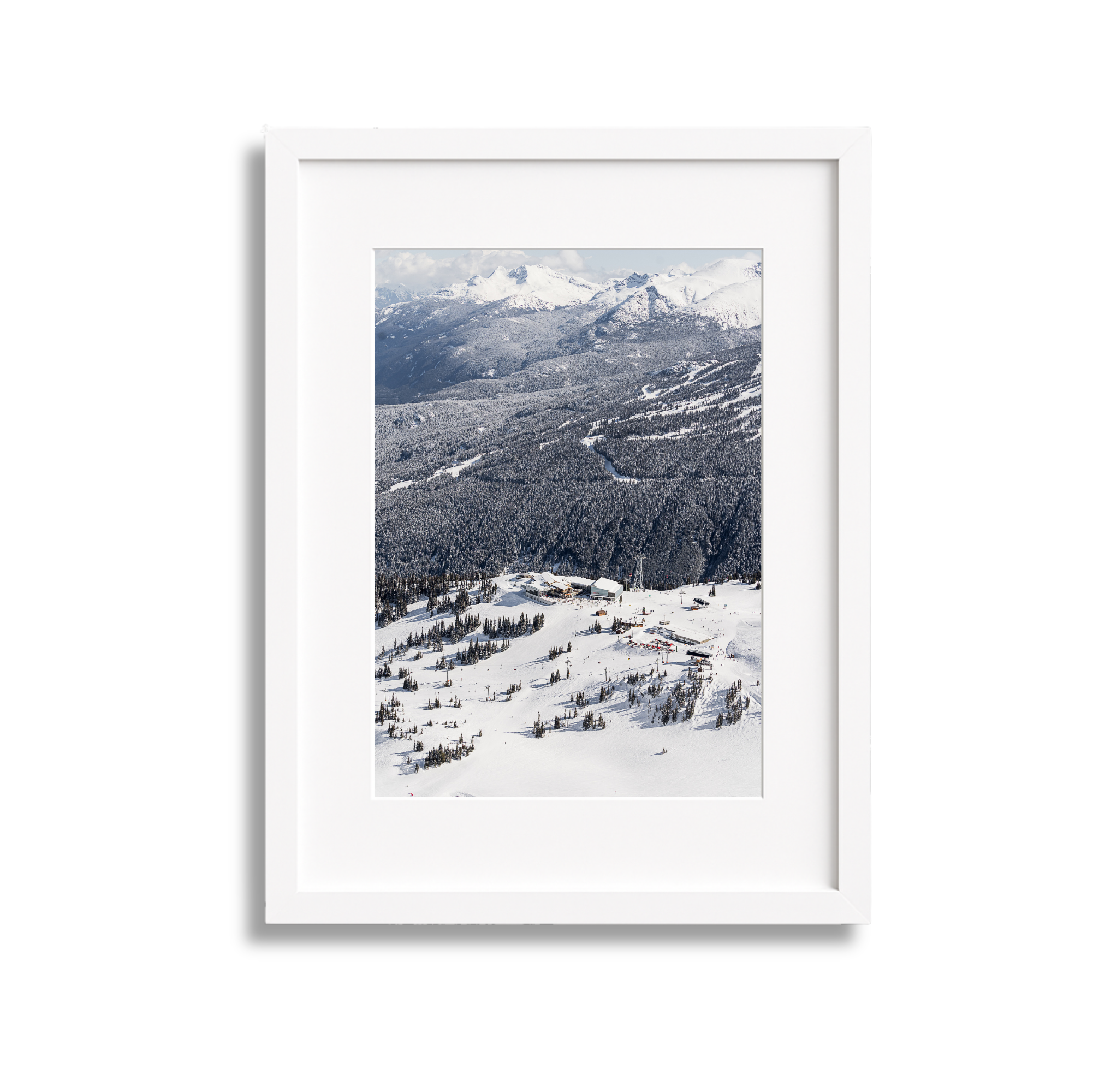 A framed photo of snow-covered mountains and a ski resort below.