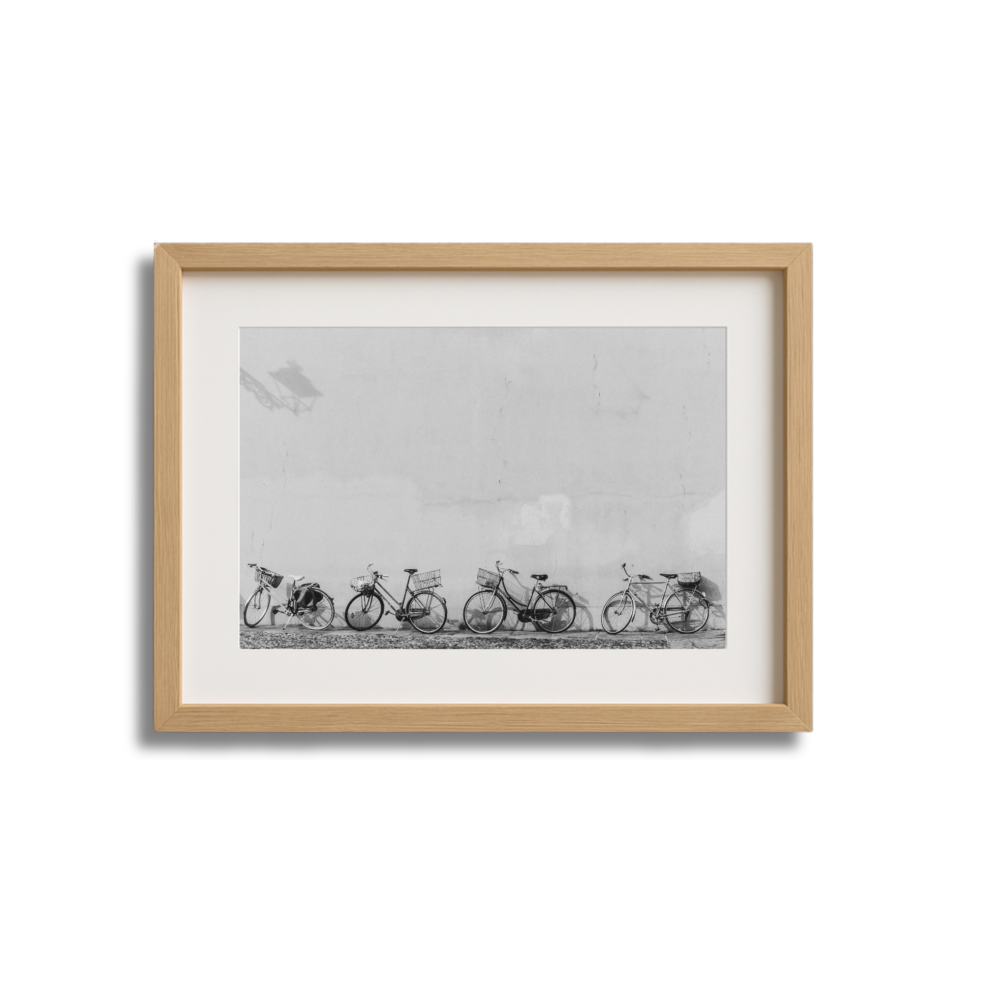 Black and white photograph of five parked bicycles leaning against a wall.