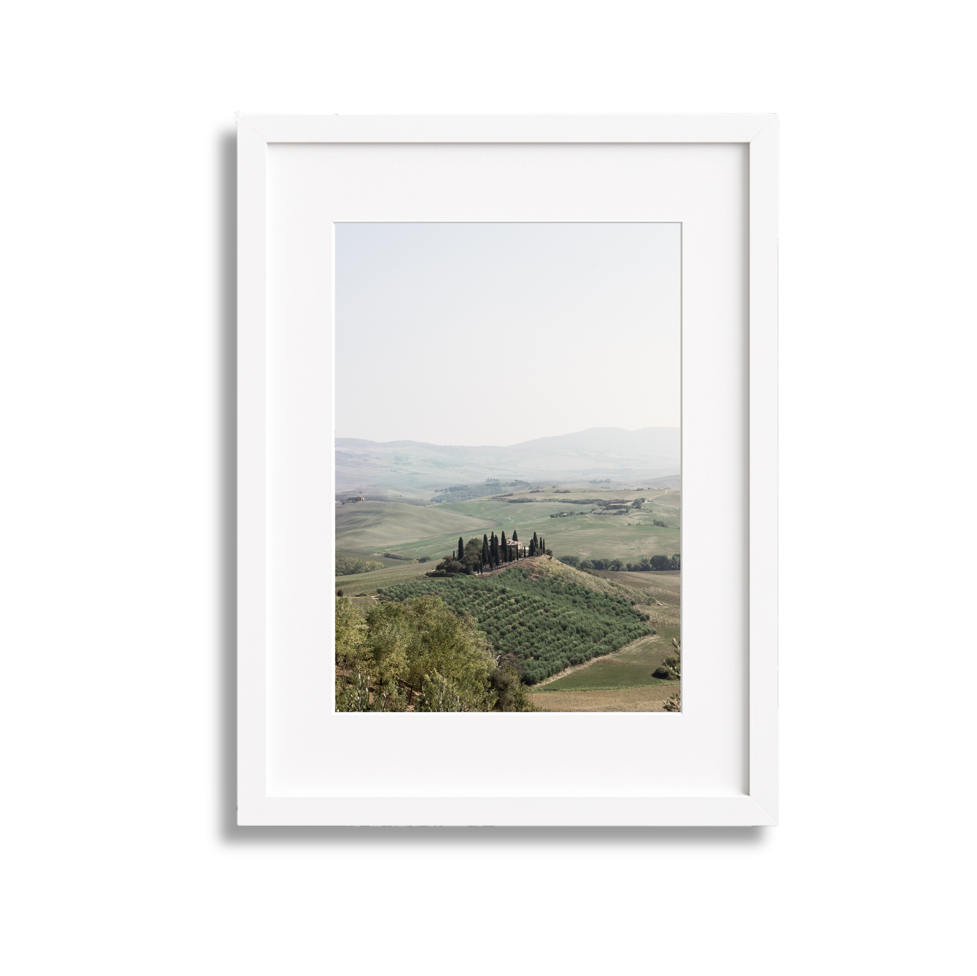 Landscape view of rolling hills with cypress trees and farmland in Tuscany, Italy, framed within a white picture frame.
